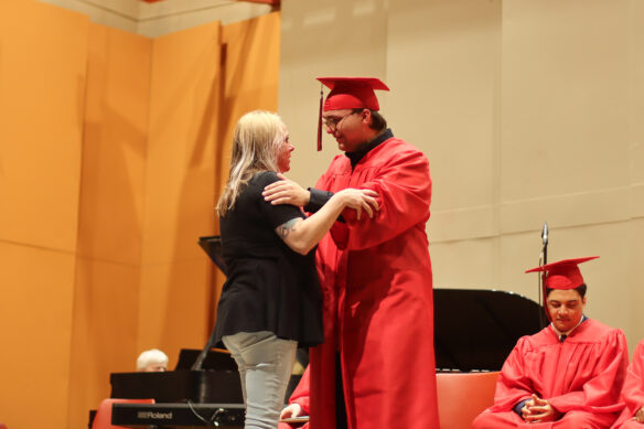 A student embraces his mother during the graduation ceremony