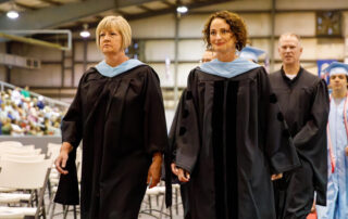 Two women stand in graduation gowns