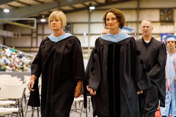 Two women stand in graduation gowns