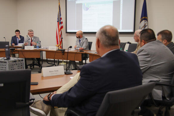 Robbie Fletcher sits at a large group of tables talking to superintendents.