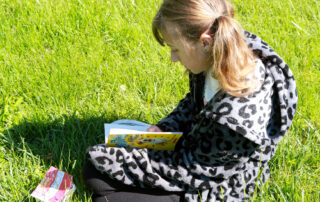 A girl reads a book in a field