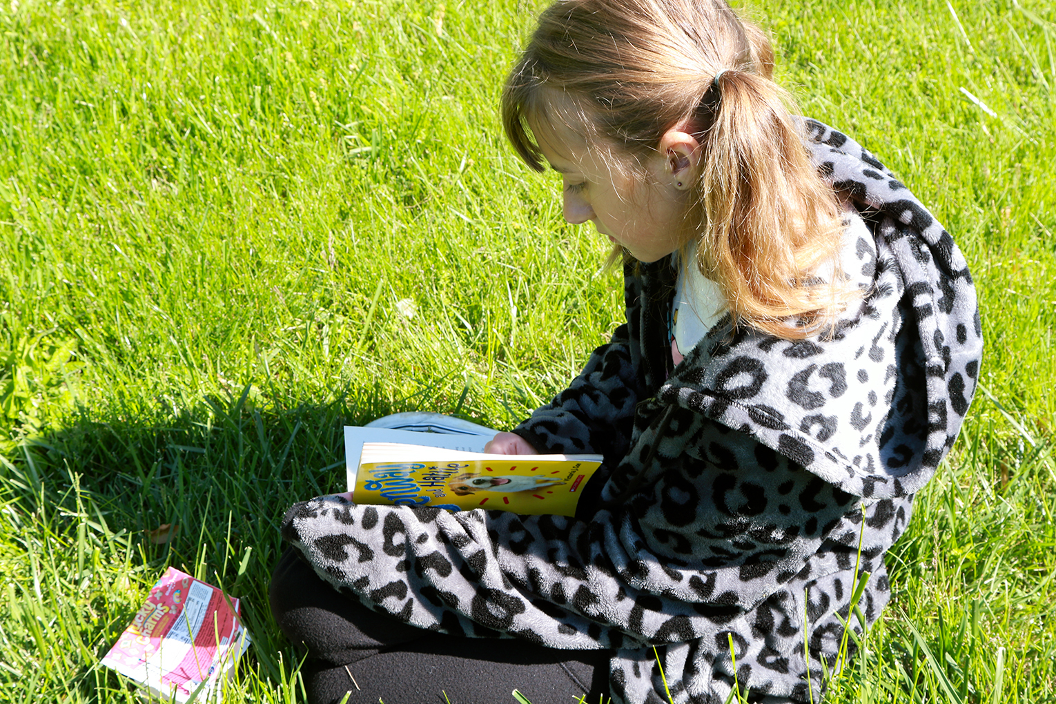 A girl reads a book in a field