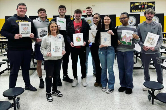 A group of students pose for a photo and hold books in their hands