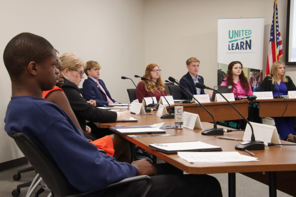 Members of KDE's Commissioner's Student Advisory Council sit around tables, listening to a presentation.