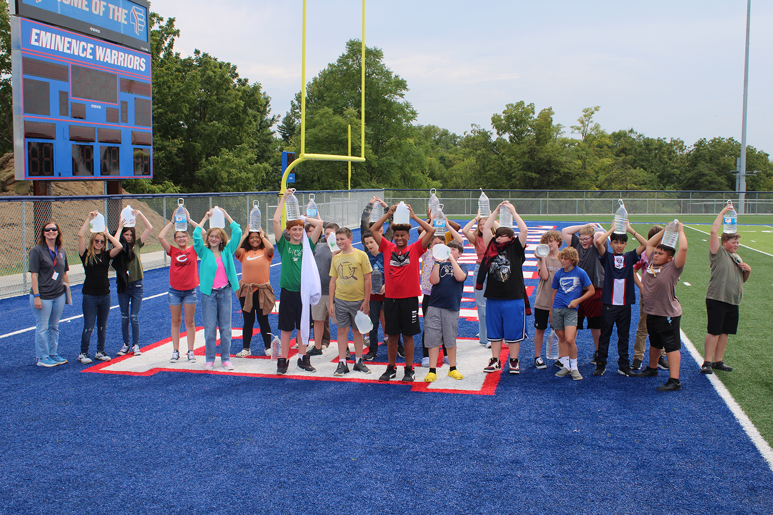 Jennifer Montgomery poses with her class as they hold water jugs above their heads