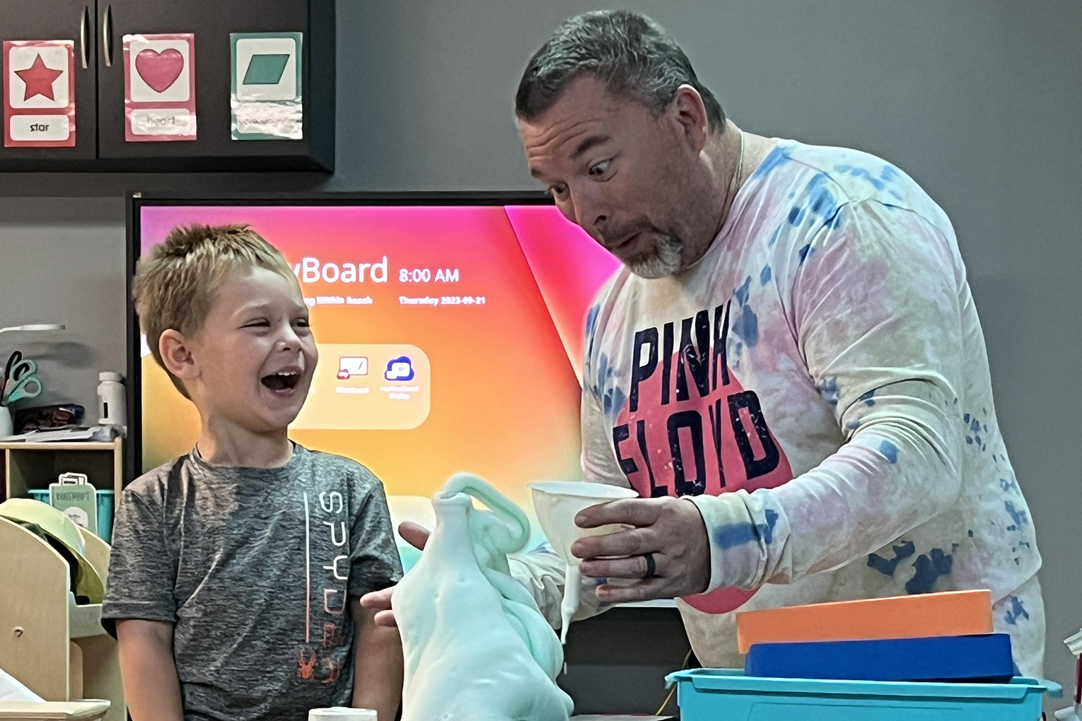 Scott Johnson does a science experiment with a student as both look shocked at the result