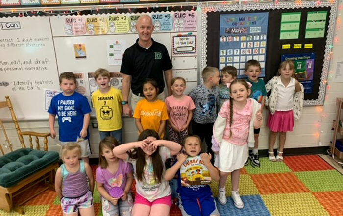 Rick Wolf stands for a photo with a classroom of kids