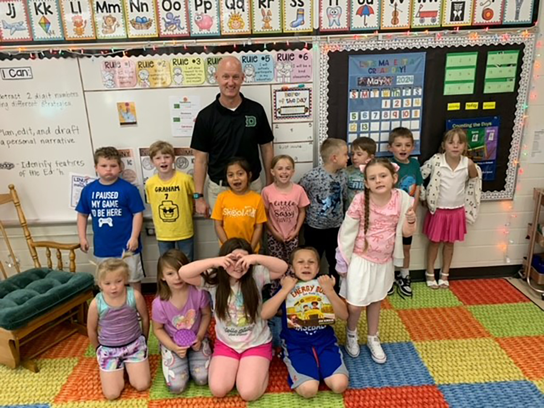 Rick Wolf stands for a photo with a classroom of kids