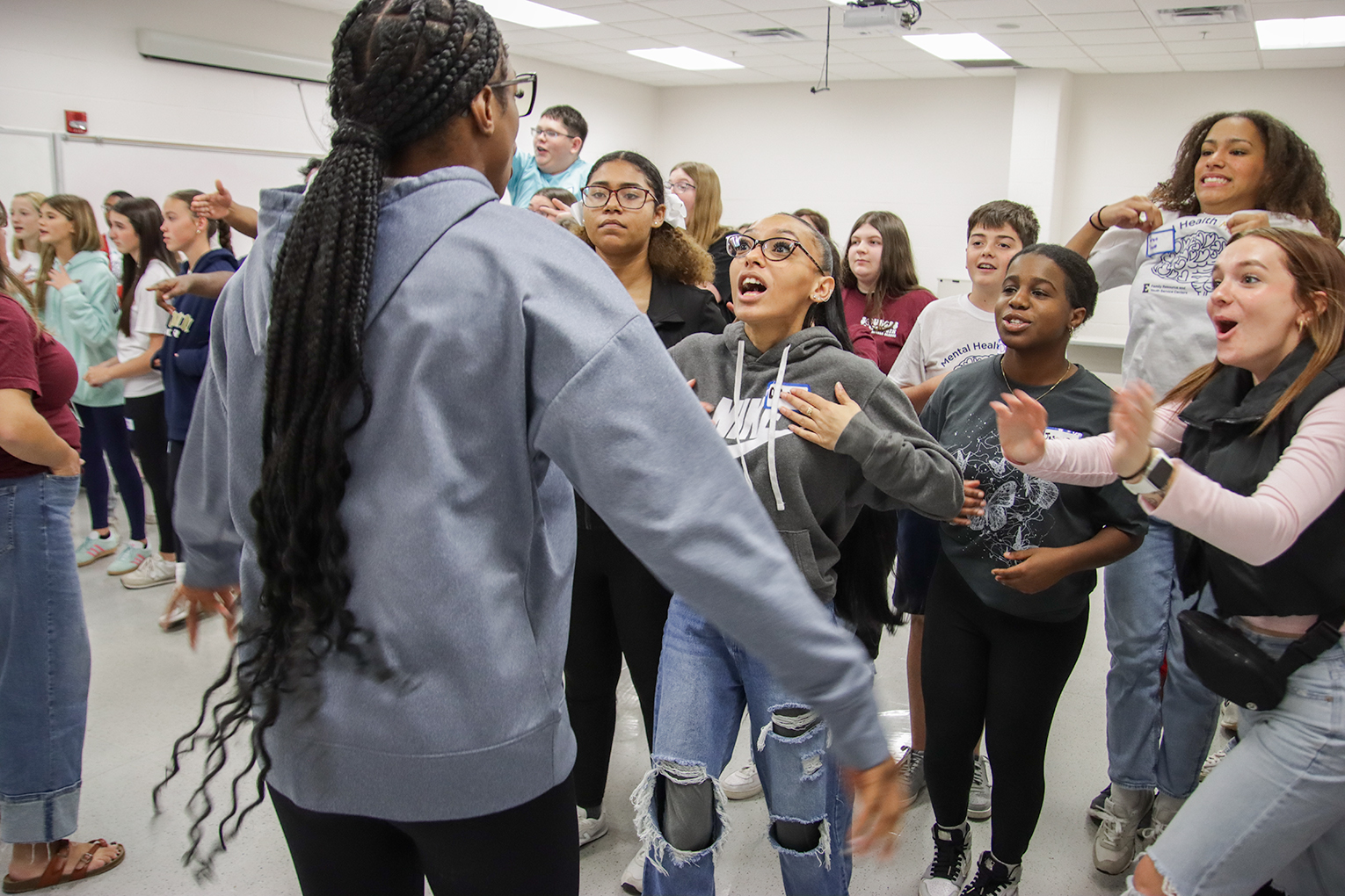 A large group of student should out guesses to a student who is acting out a phrase.