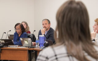 Juston Pate looks at Jennifer Stafford as she makes a presentation while Diana Woods, seated next to Pate, looks at her computer screen